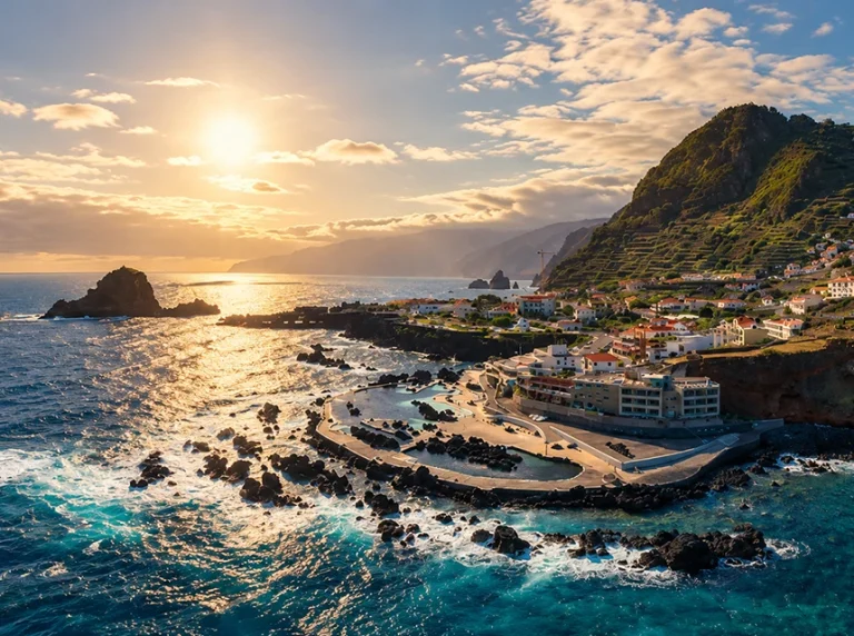 Costa de Porto Moniz ao pôr do sol, com piscinas junto ao mar e rochas vulcânicas.